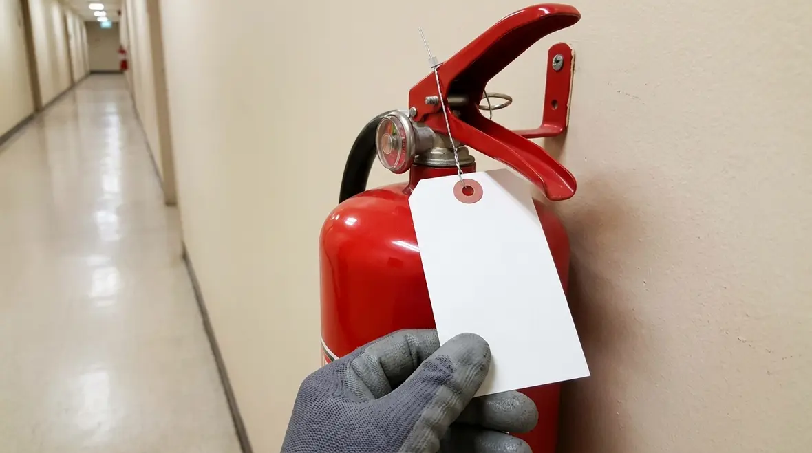 Technician attaching a fire extinguisher tagging label