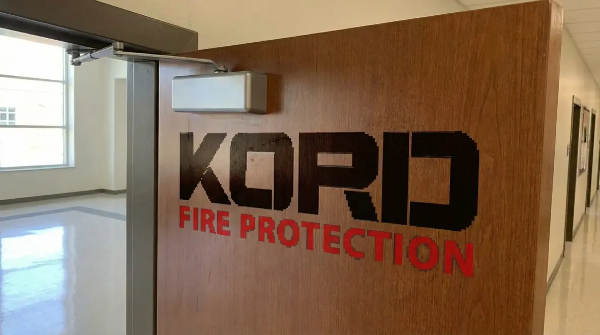 Technician inspecting school fire alarm and sprinkler controls