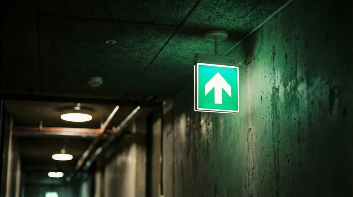 Emergency exit sign with directional arrow in commercial hallway
