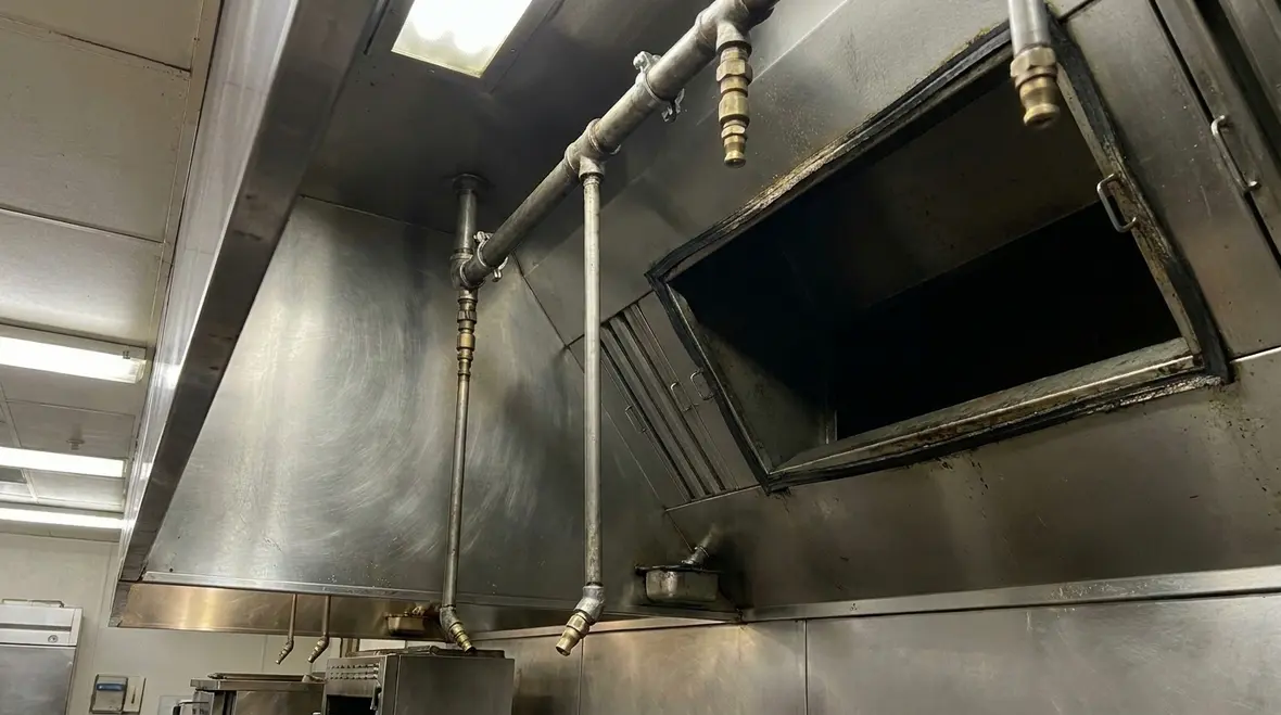 Technician inspecting commercial kitchen fire suppression coverage and components