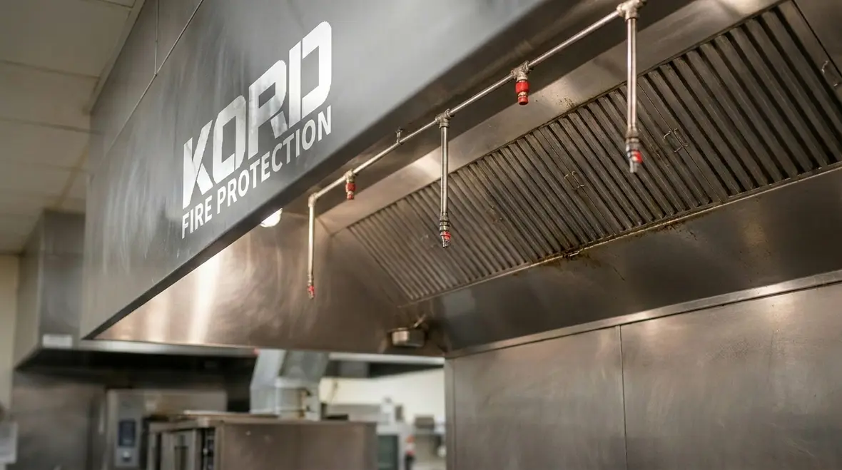 Commercial kitchen fire suppression nozzles positioned over cooking equipment