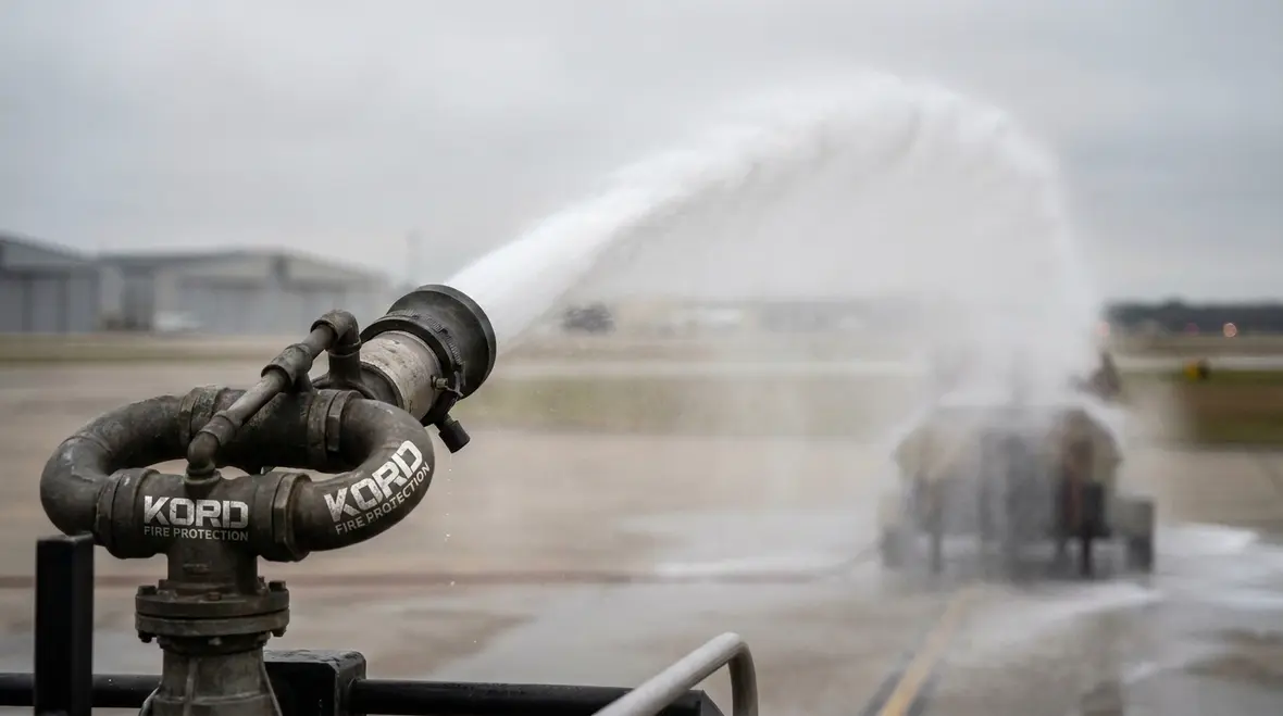 Mounted ARFF turret nozzle delivering foam stream across an aircraft hazard area